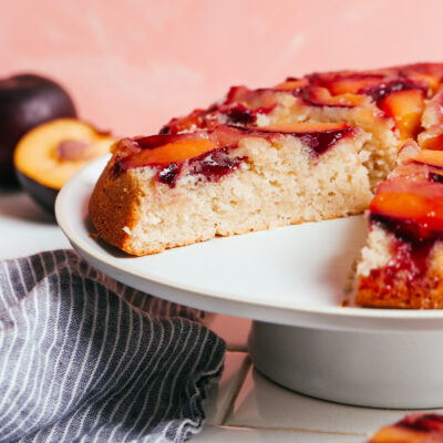 Partially sliced plum upside down cake on a cake stand