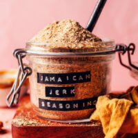 Close up shot of our homemade Jamaican jerk seasoning in a jar with a spoon in it