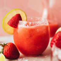 Glass of our fresh strawberry margarita recipe with a slice slice and strawberry on the rim