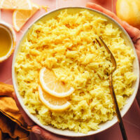 Hands holding a bowl of our easy vegan Greek-inspired lemon rice