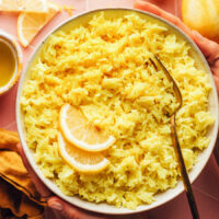 Bowl of our easy lemon rice recipe topped with slices of fresh lemon