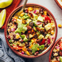 Close up shot of a bowl of southwest quinoa black bean salad topped with avocado and chili lime pepitas