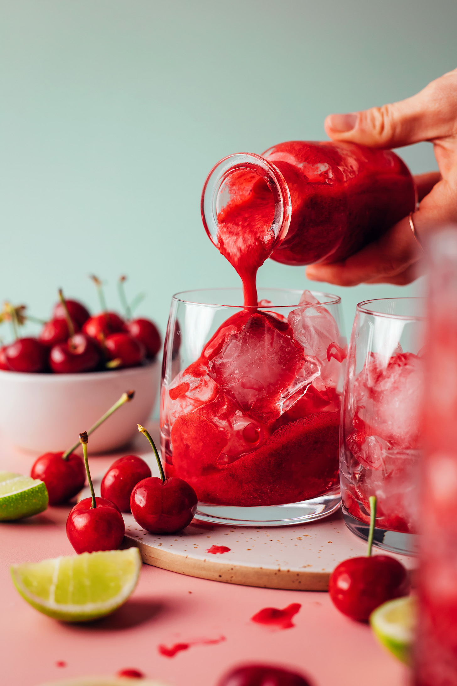 Pouring cherry lime concentrate over ice in a glass