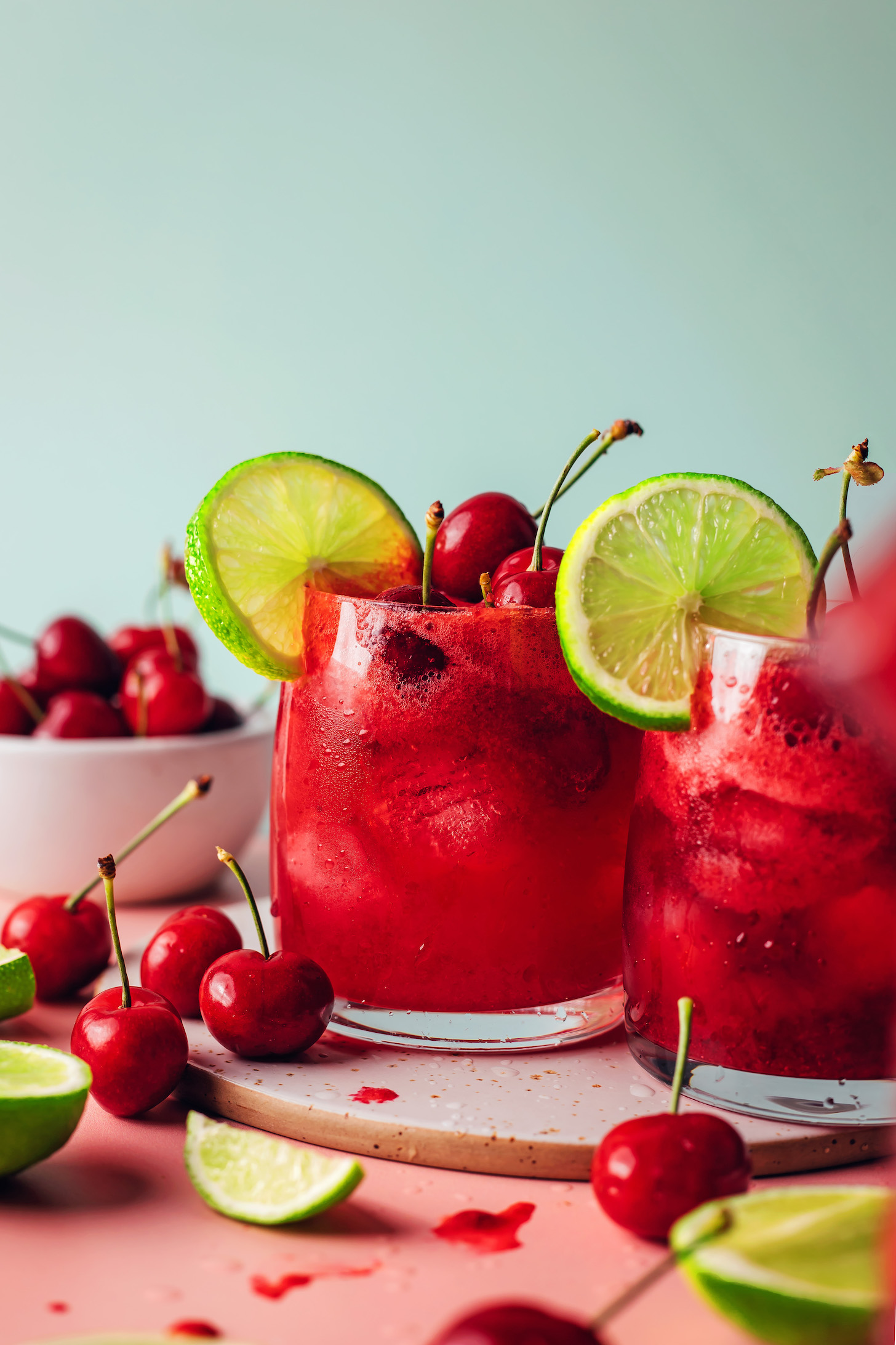 Two glasses of homemade cherry limeade with fresh cherries and lime slices