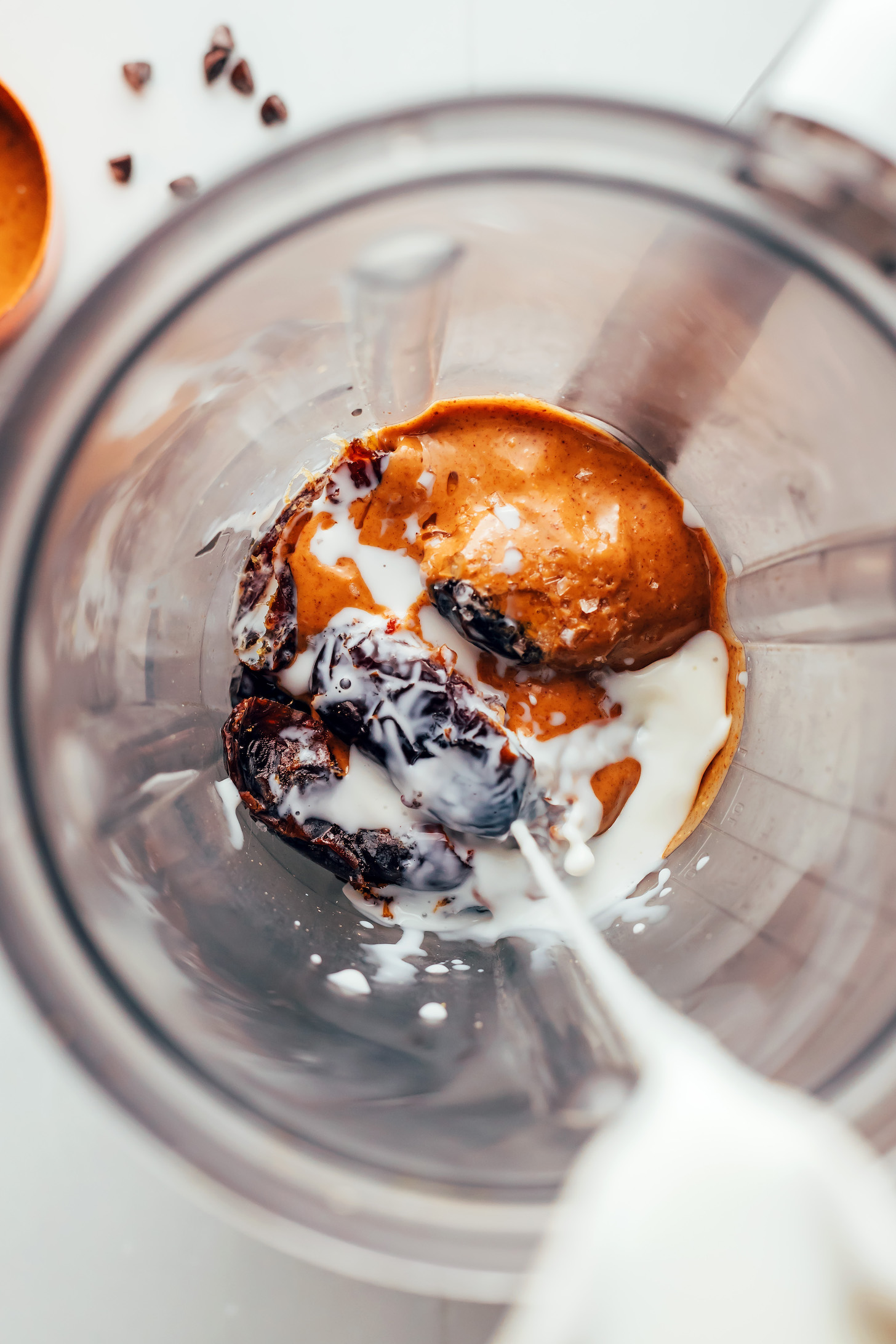 Pouring dairy-free milk into a blender with dates and peanut butter