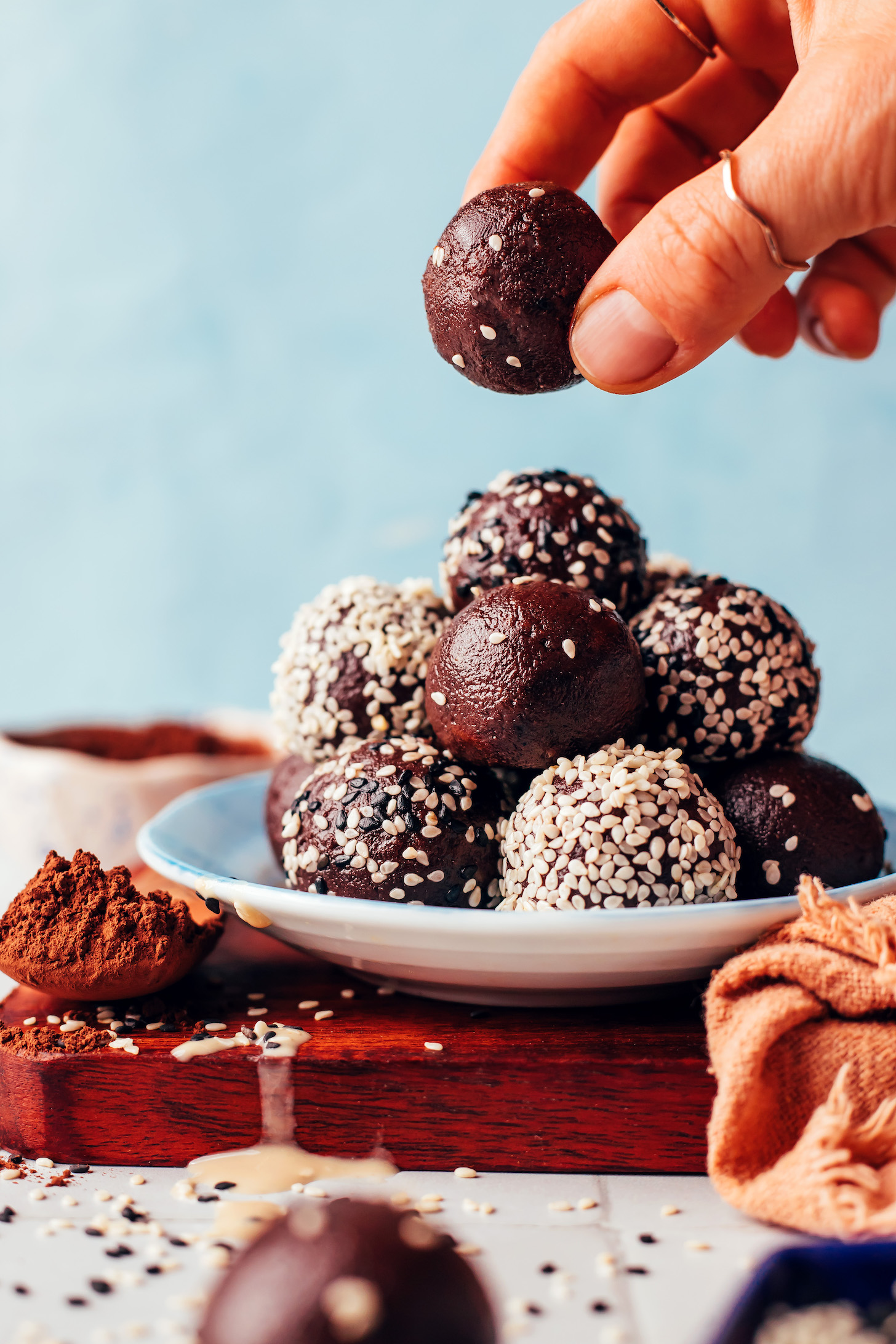 Picking up a vegan chocolate tahini truffle from a plate with a stack of truffles