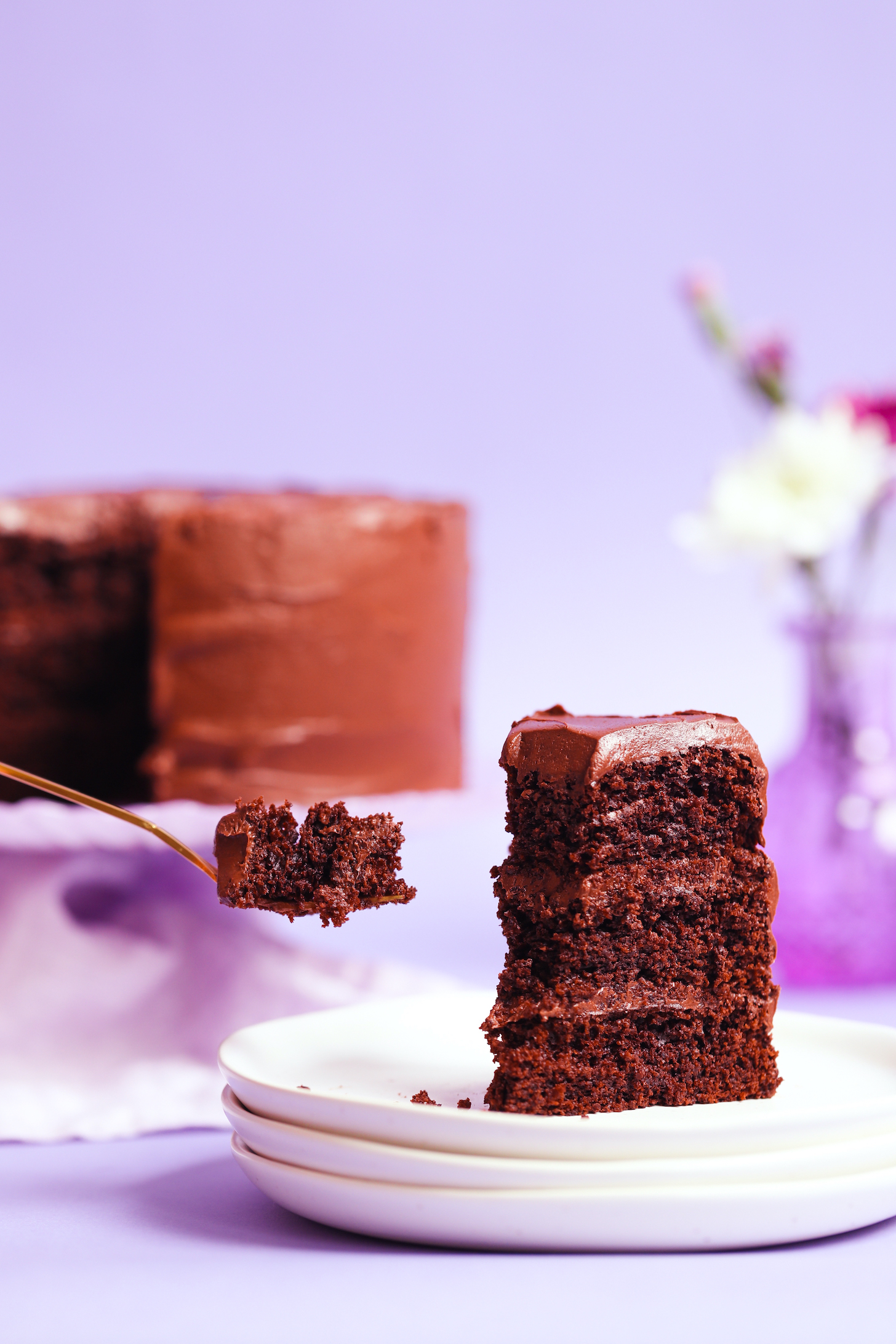 Bite of gluten-free chocolate cake resting on a fork next to a slice of cake