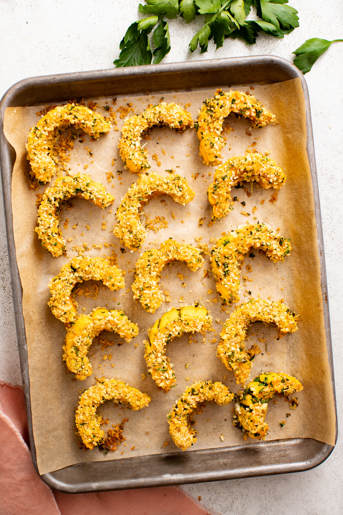 Breaded roasted delicata squash on a parchment-lined baking sheet