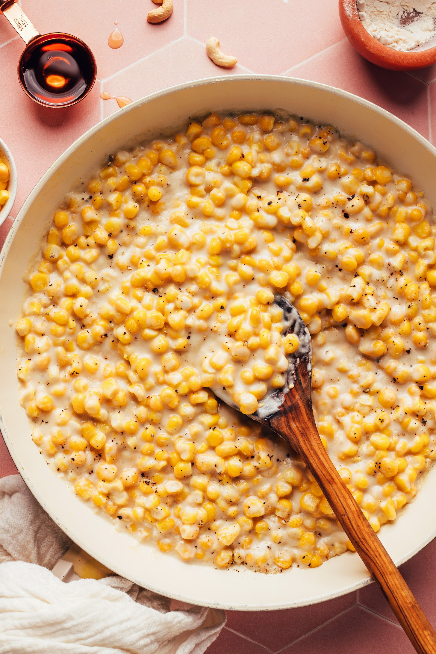 Wooden spoon in a skillet of our easy vegan creamed corn recipe