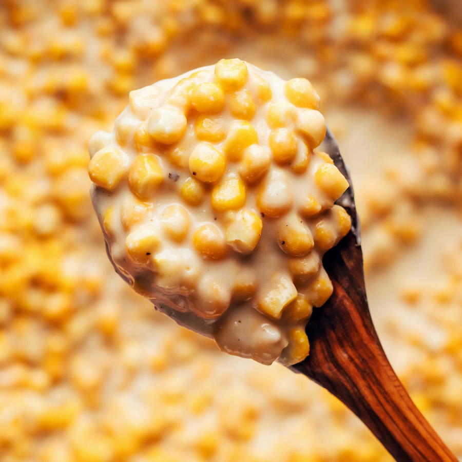 Holding a spoon of vegan creamed corn over a pan