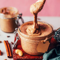 Chai-spiced nut butter dripping off a spoon into a jar
