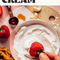 Dipping a strawberry into a bowl of vegan whipped cream