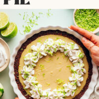 Hands holding a pie plate filled with vegan key lime pie