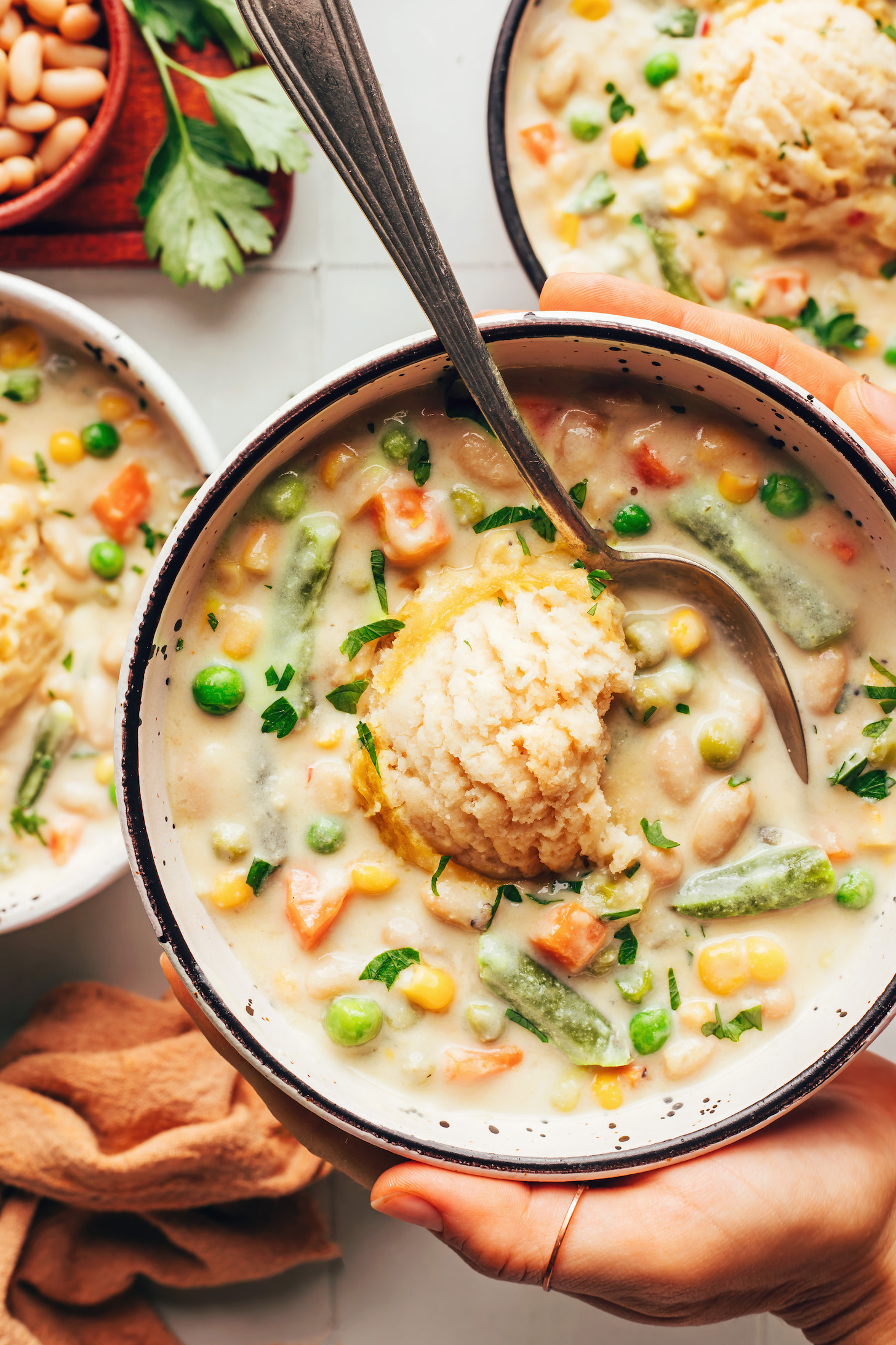 Hands holding a bowl of vegan white bean pot pie soup