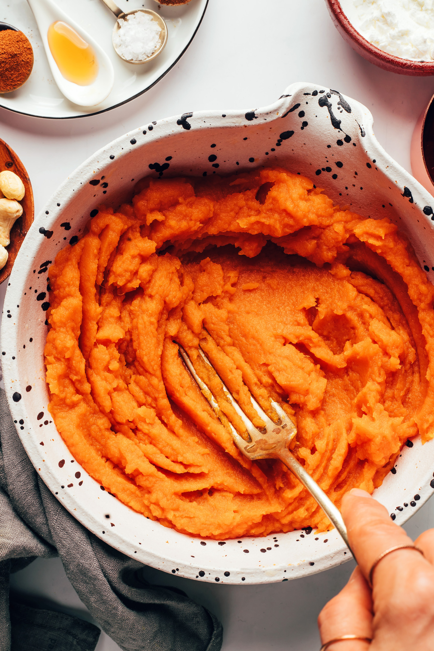 Using a fork to mash roasted sweet potato in a bowl