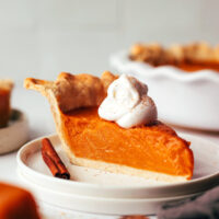 Slice of vegan sweet potato pie on a plate topped with cashew whipped cream