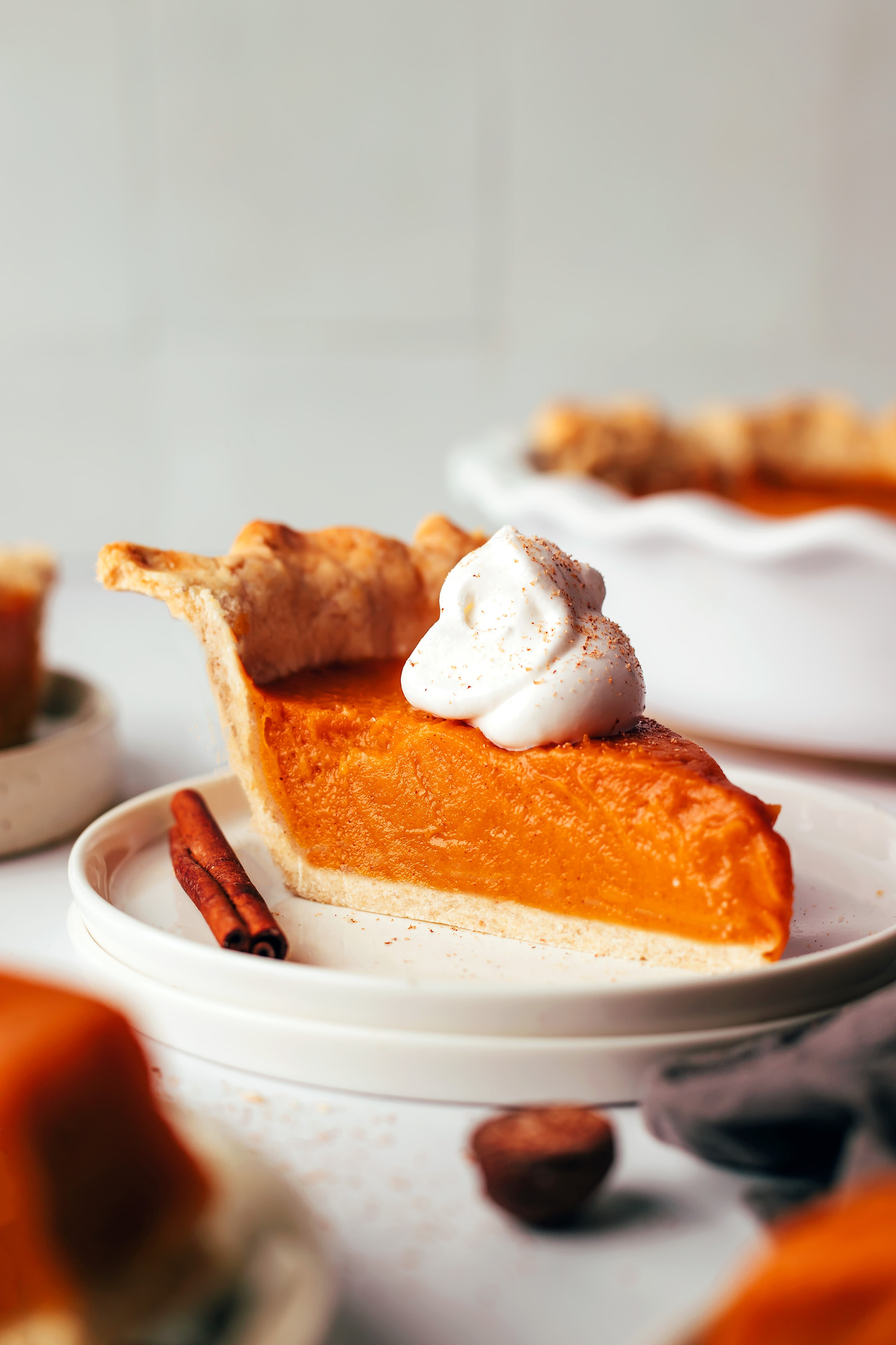 Slice of sweet potato pie on a plate topped with coconut whipped cream