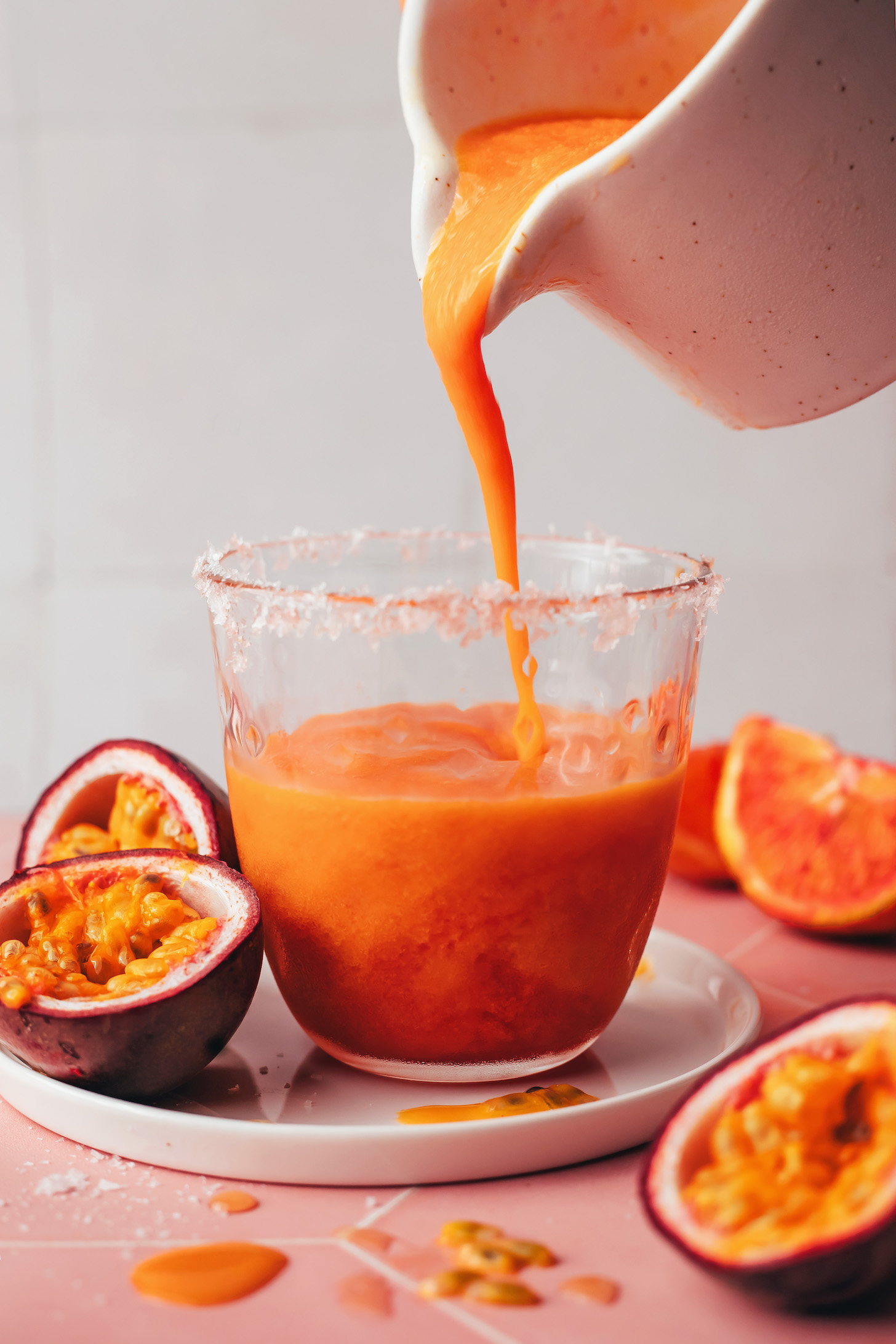 Pouring a blood orange passion fruit mezcalita into a glass