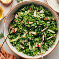 Serving spoons in a bowl of vegan kale apple slaw