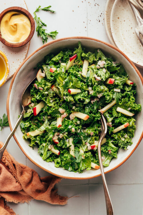 Serving spoons in a bowl of vegan kale apple slaw