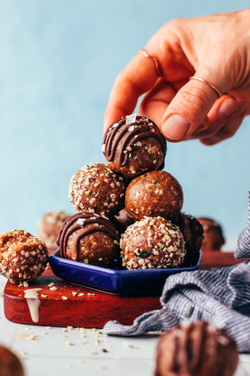 Picking up a nut-free tahini snack bites from a stack of more energy bites