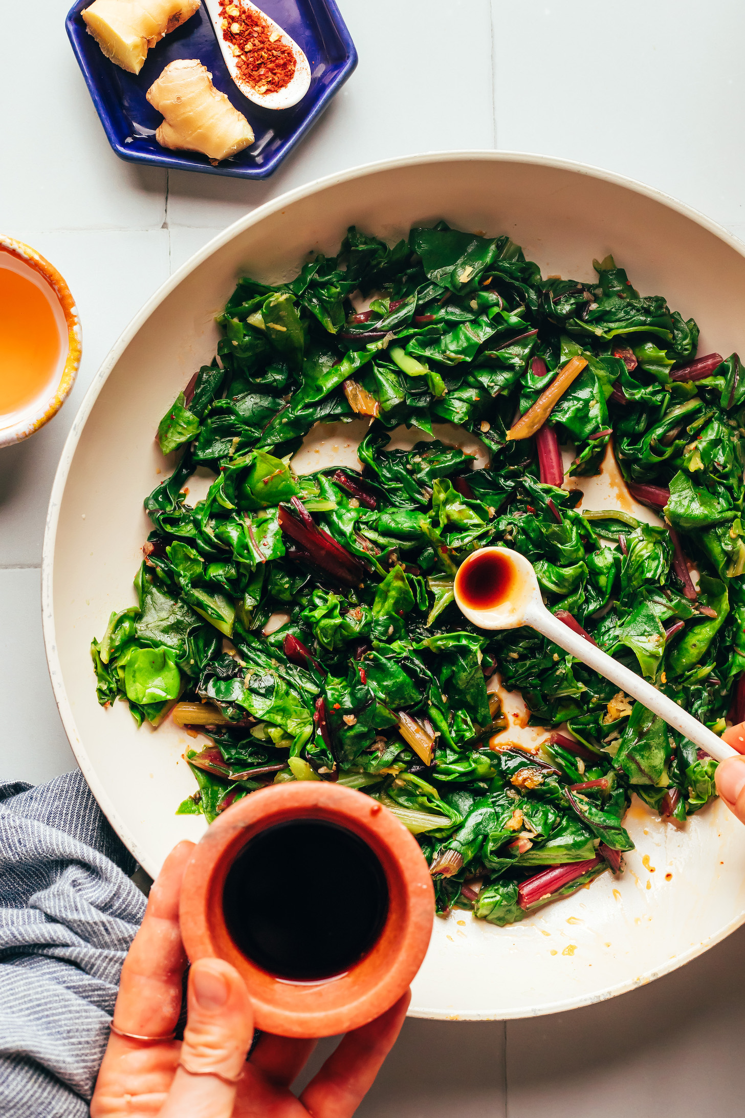 Adding tamari to greens for salty, Asian-inspired flavor