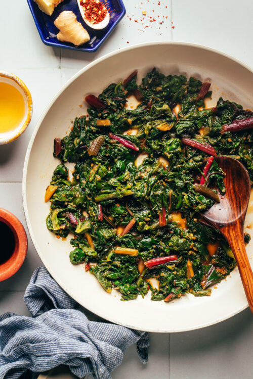 Wooden spoon in a skillet of our easy sautéed swiss chard recipe