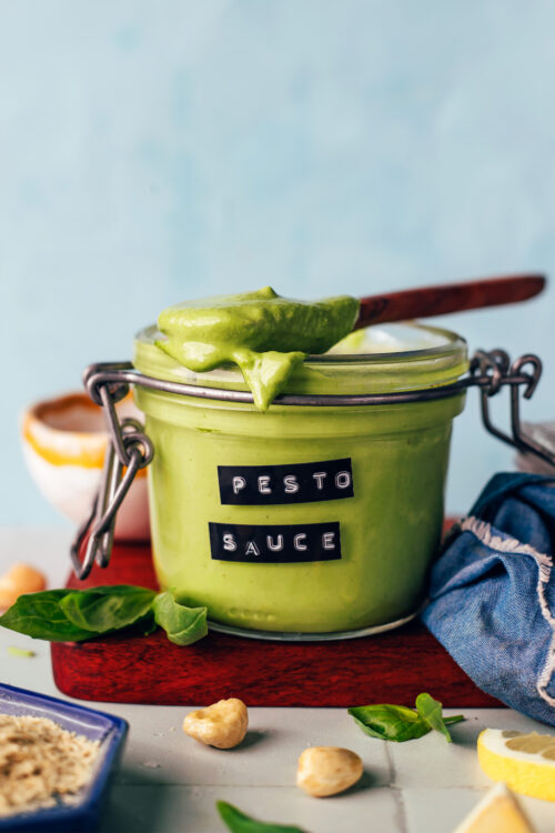 Spoonful of creamy pesto sauce resting on top of a jar of more sauce
