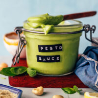 Spoonful of pesto sauce resting on top of a jar