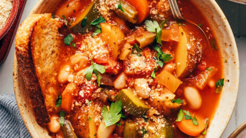 Bowl of white bean minestrone with a slice of bread in it