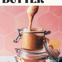 Homemade chai-spiced nut butter dripping from a spoon into a jar