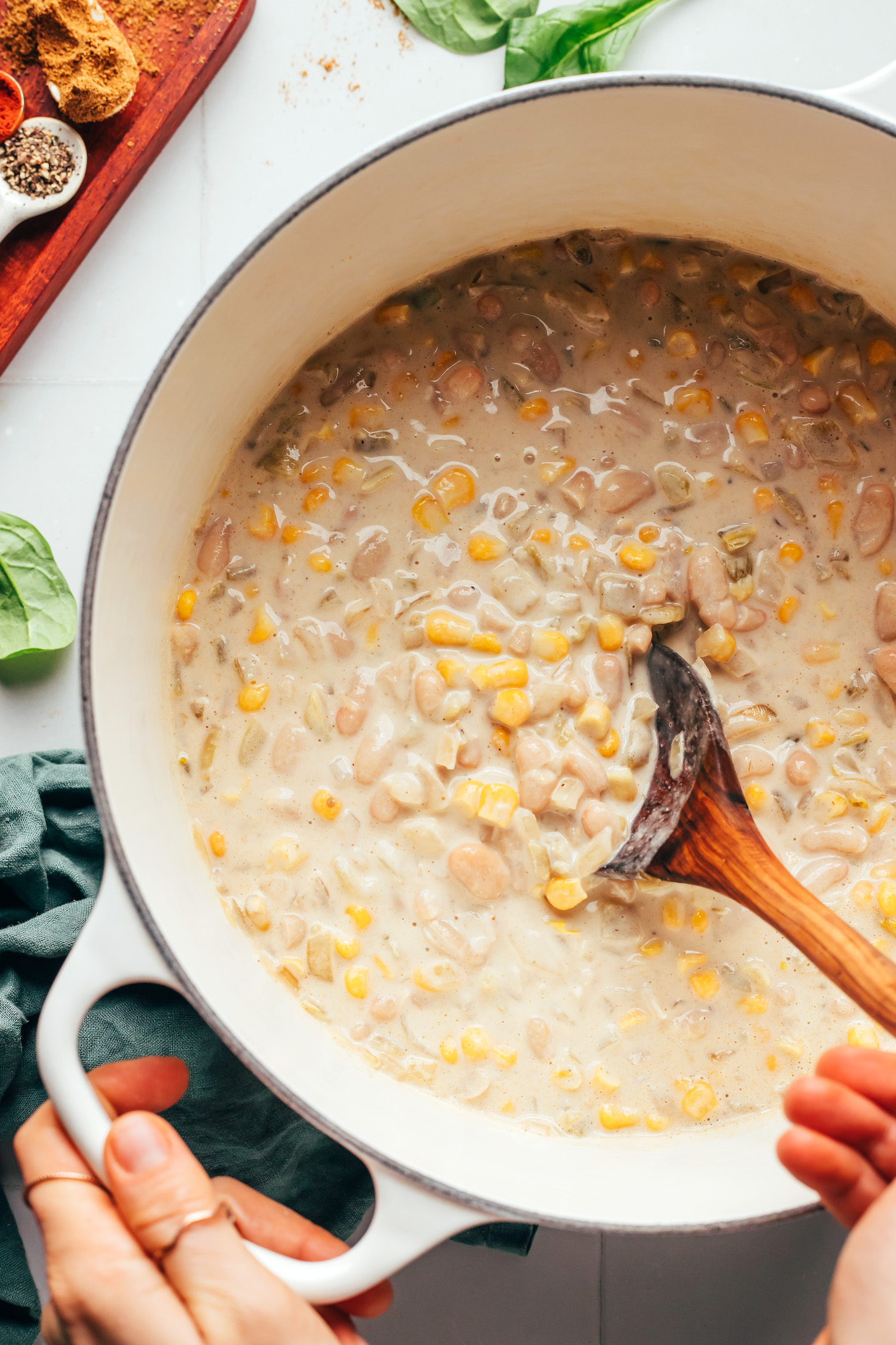 Stirring a creamy corn and white bean mixture in a pot