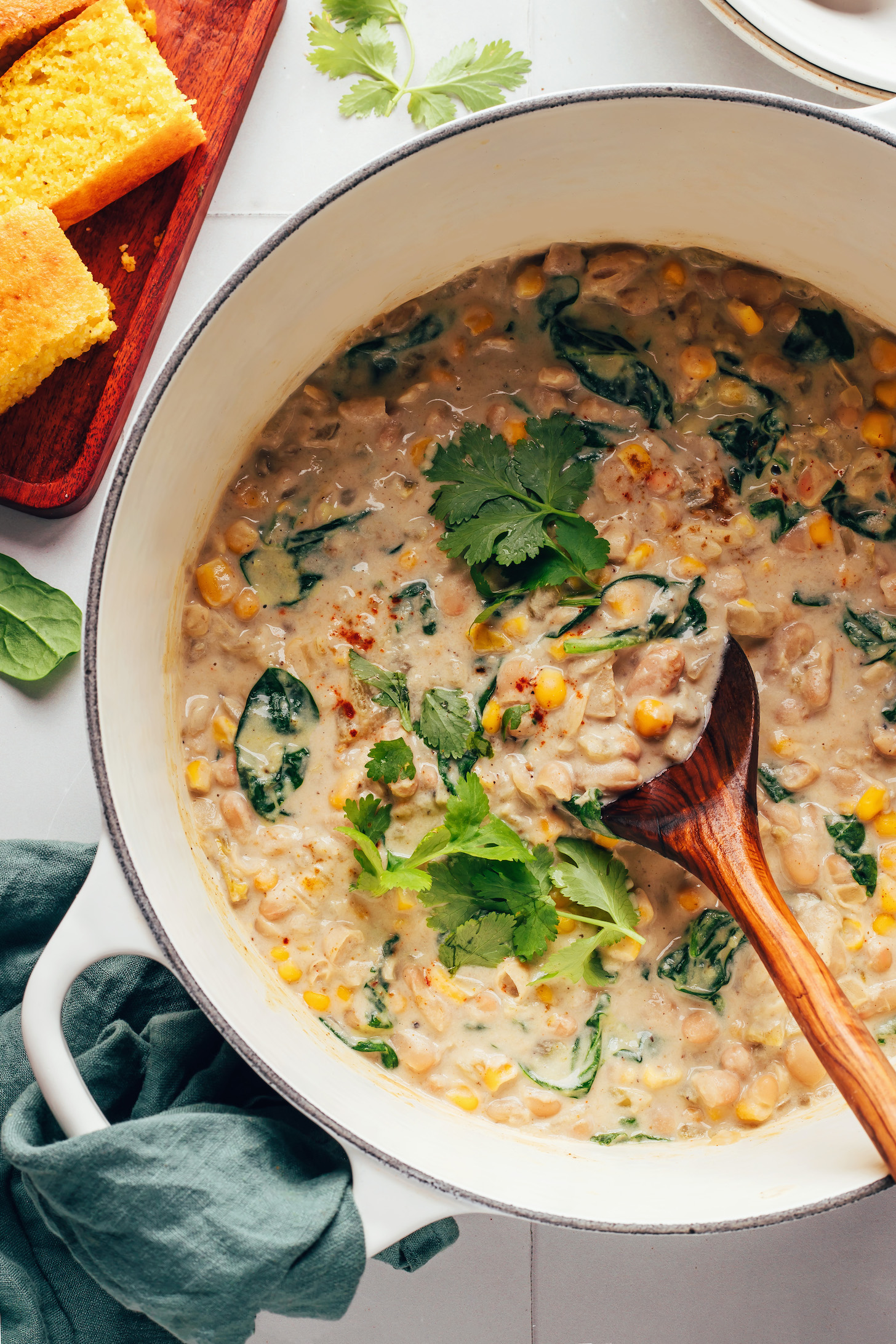 Dutch oven of our vegan white bean chili next to slices of cornbread