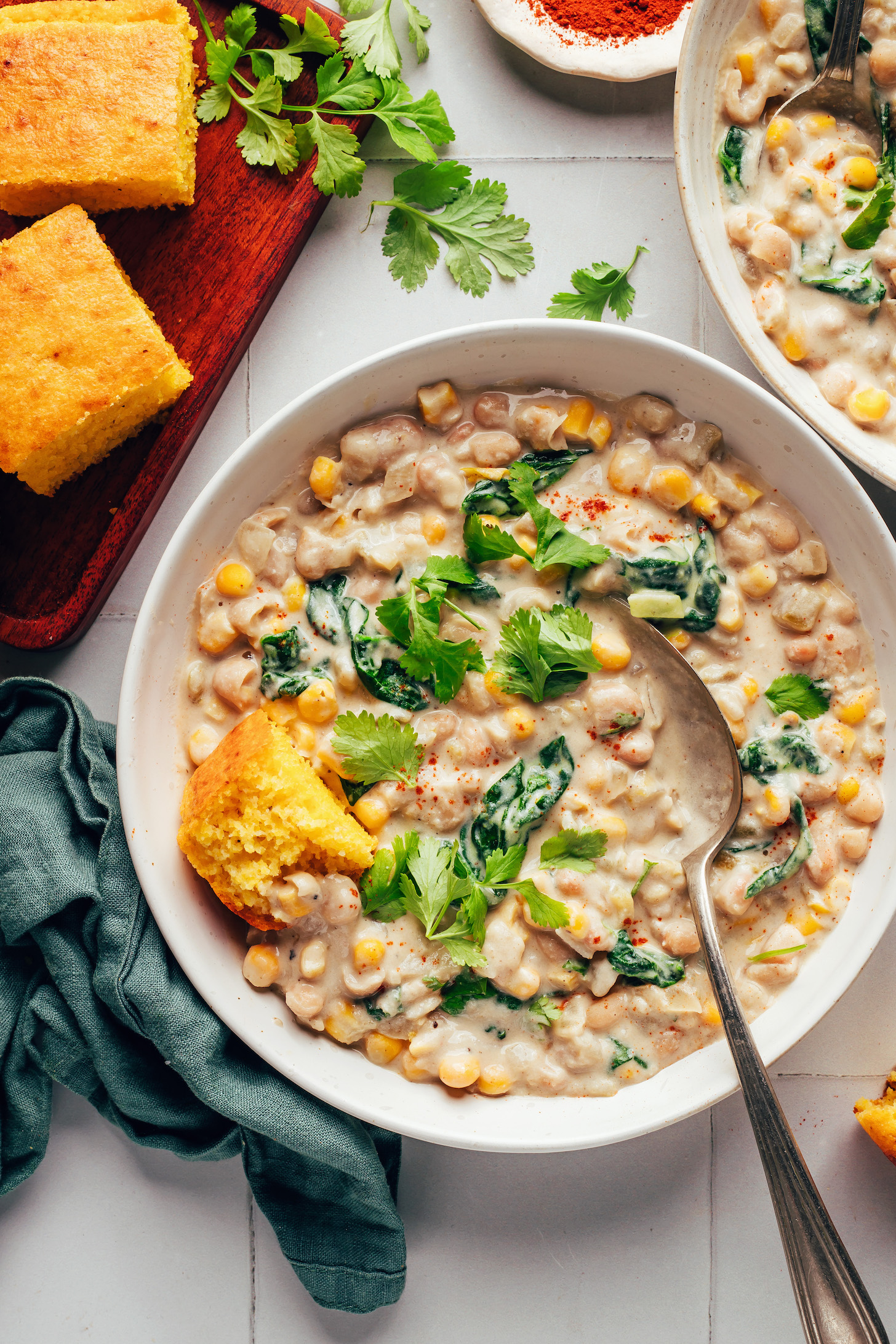 Slices of cornbread next to bowls of vegan white bean chili