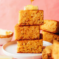 Stack of slices of gluten-free cornbread topped with butter and a drizzle of honey