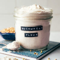 Buckwheat groats next to a jar of homemade buckwheat flour