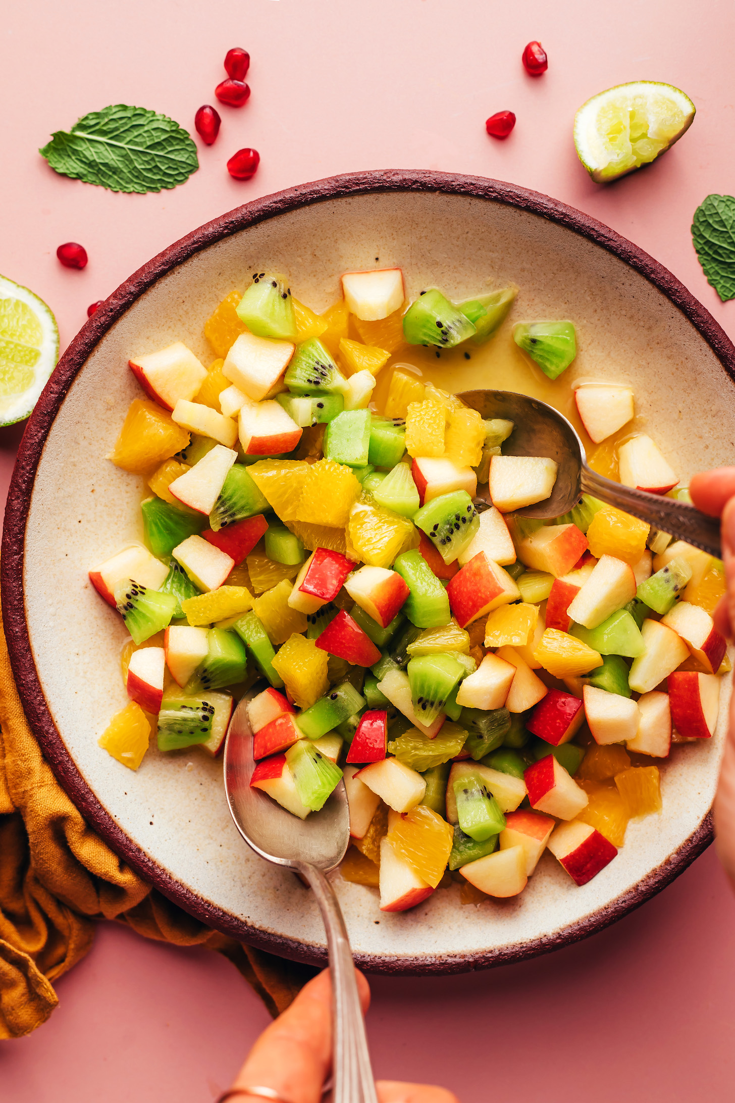 Using serving spoons to toss a fresh winter fruit salad