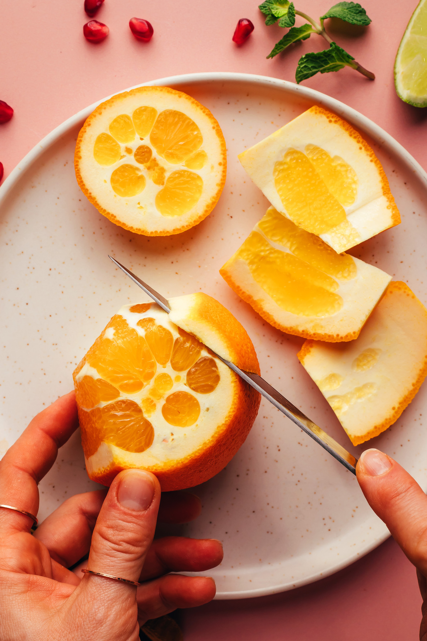 Using a sharp knife to remove the peel from an orange