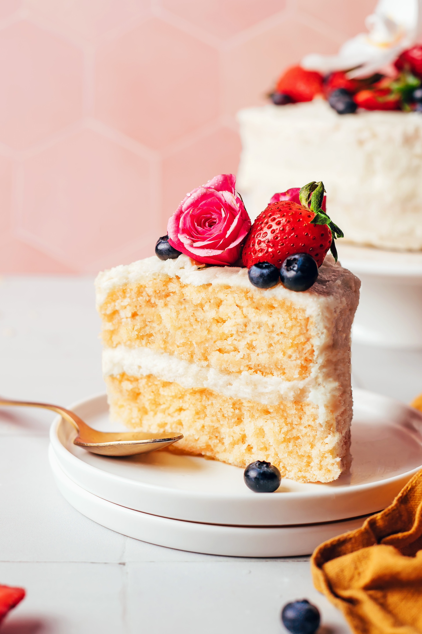 Slice of gluten-free vanilla cake decorated with vanilla buttercream frosting and fresh berries