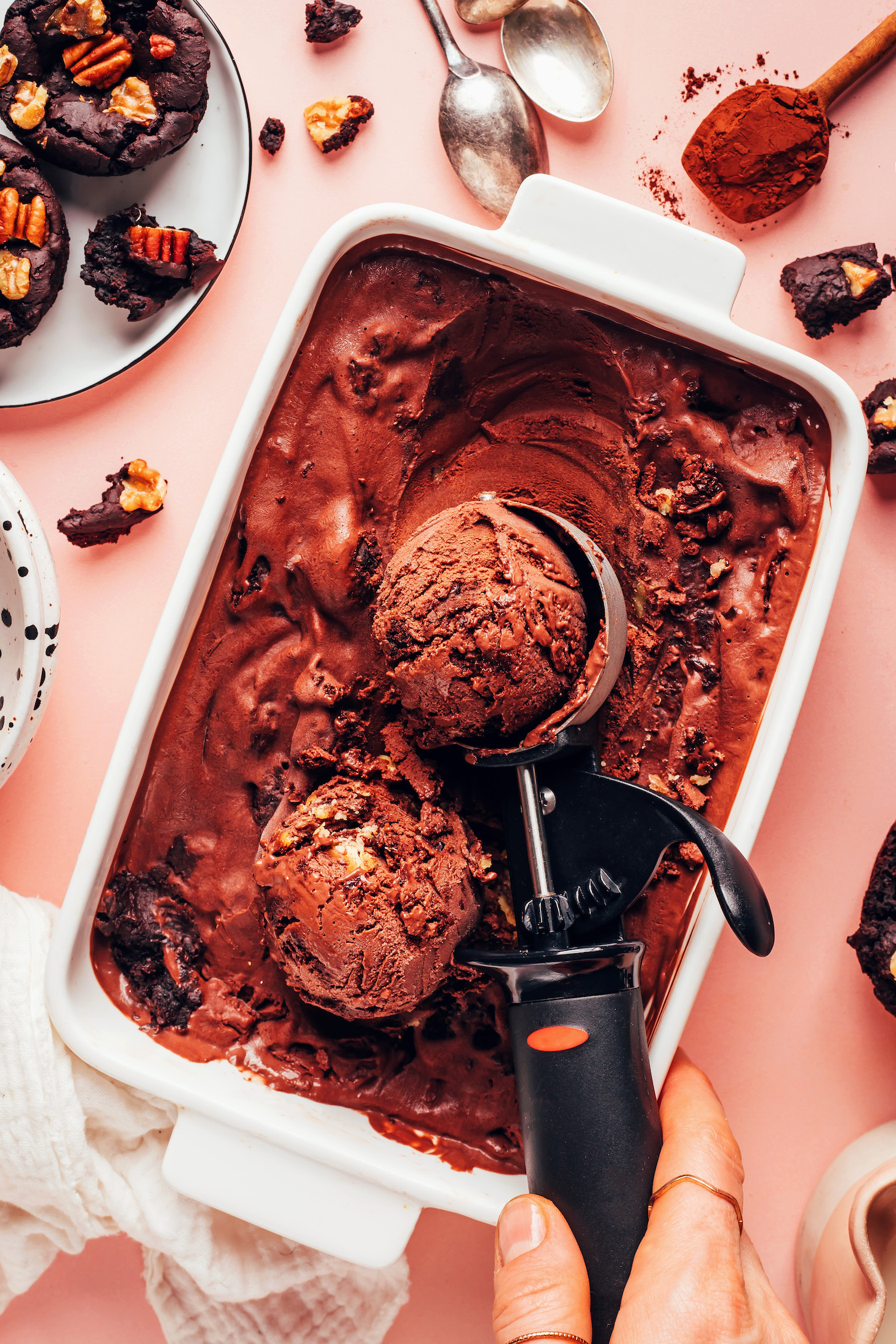 Scoops of vegan chocolate brownie ice cream in a dish and ice cream scoop