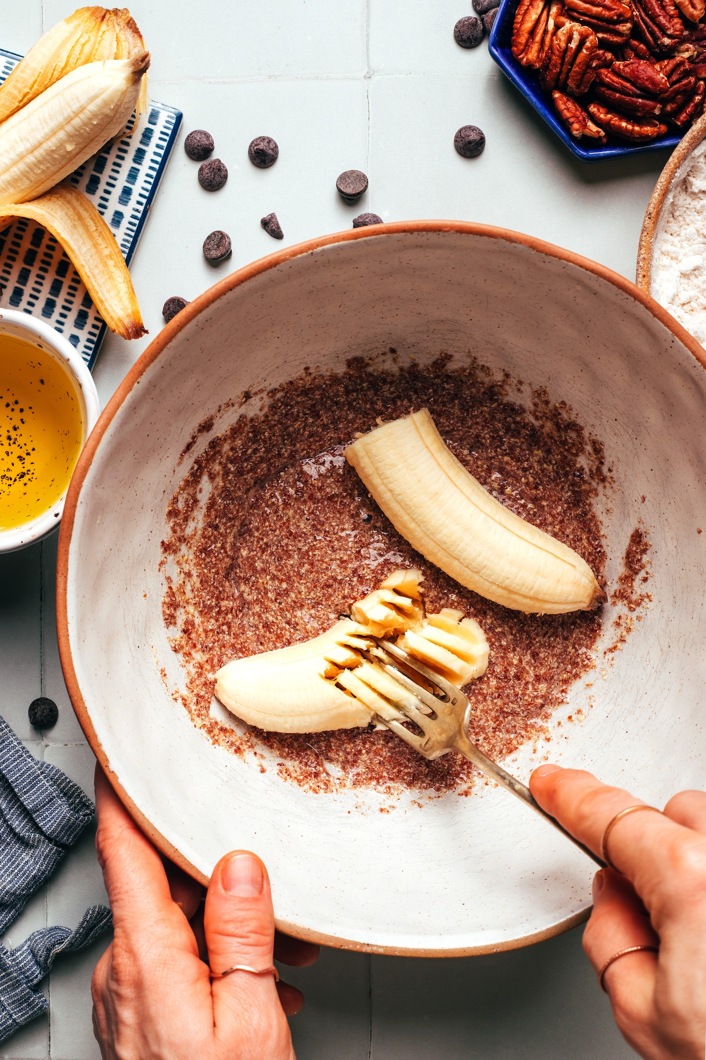 Mashing banana in a mixing bowl with flax eggs