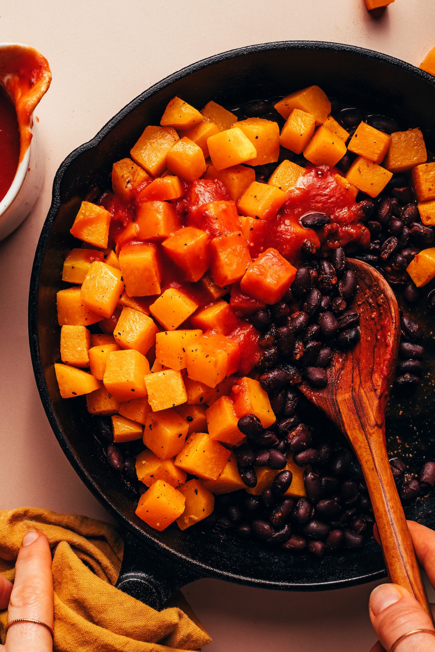 Cast iron skillet with black beans, roasted butternut squash, and homemade enchilada sauce