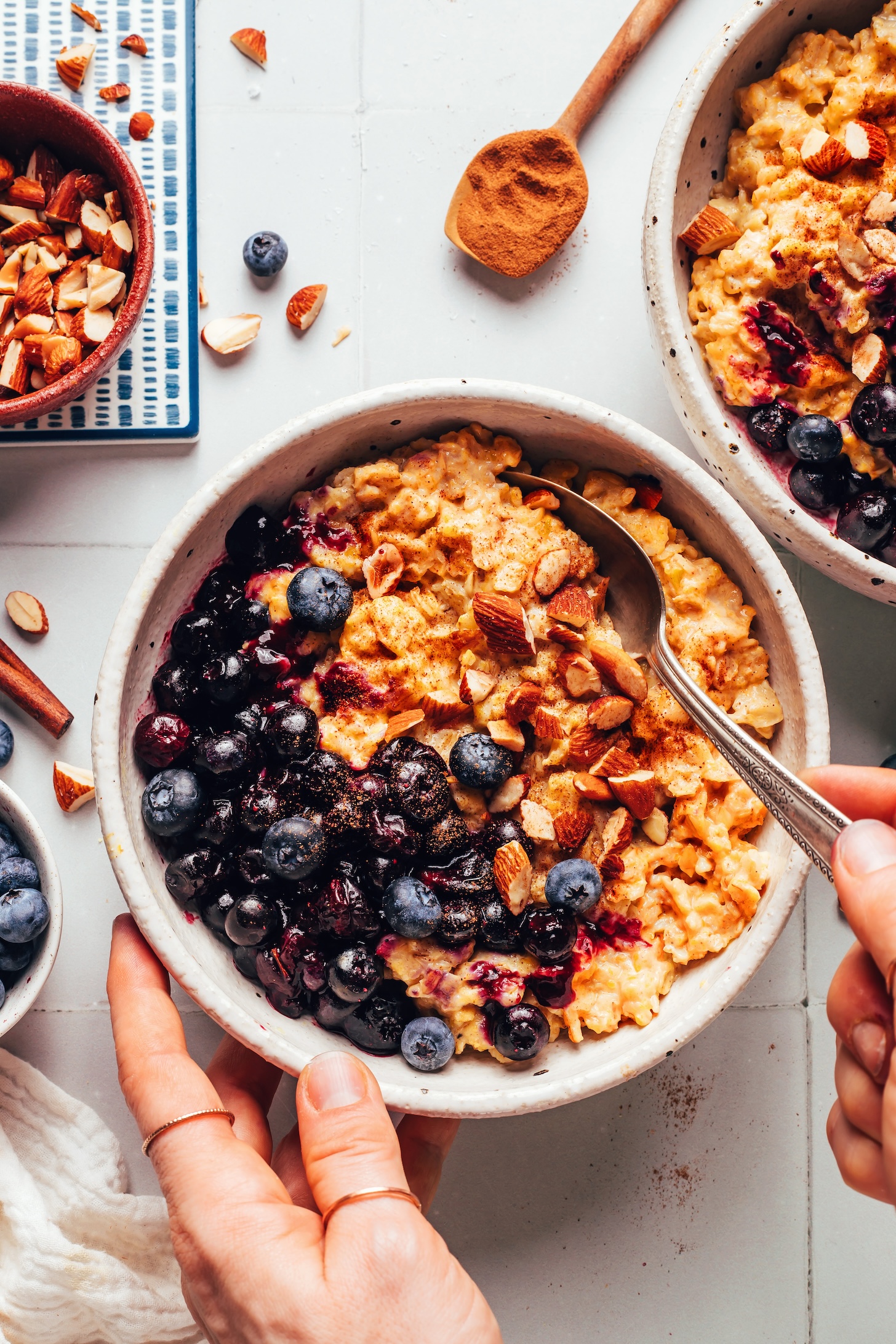 Two bowls of creamy pumpkin oats topped with blueberries and toasted almonds