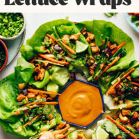 Using a spoon to add sauce to a vegan lettuce wrap