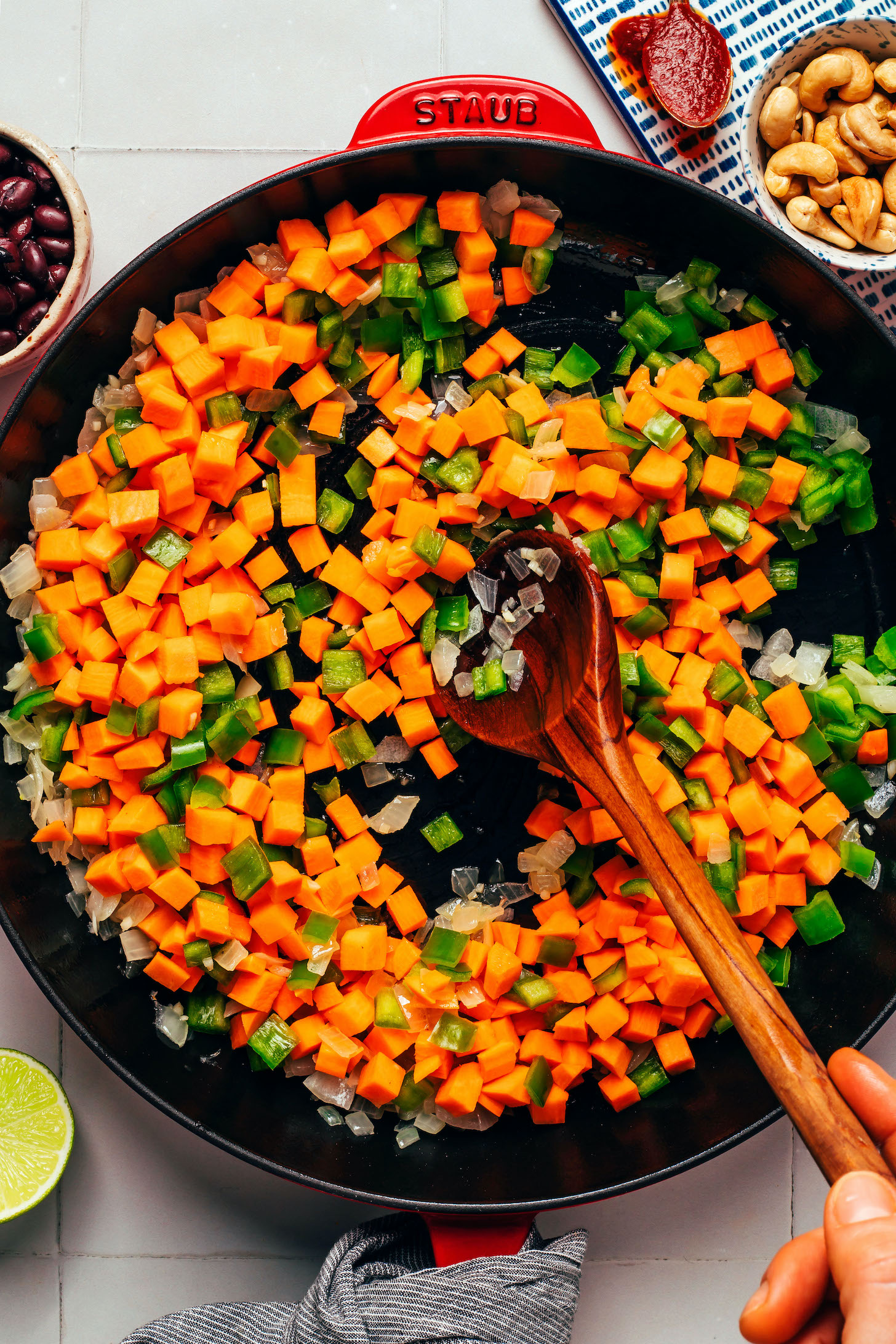 Sautéing onions, sweet potatoes, and bell peppers in a skillet