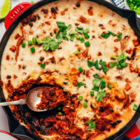 Overhead photo of a spoon resting in a pan of our cheesy vegan enchilada skillet recipe