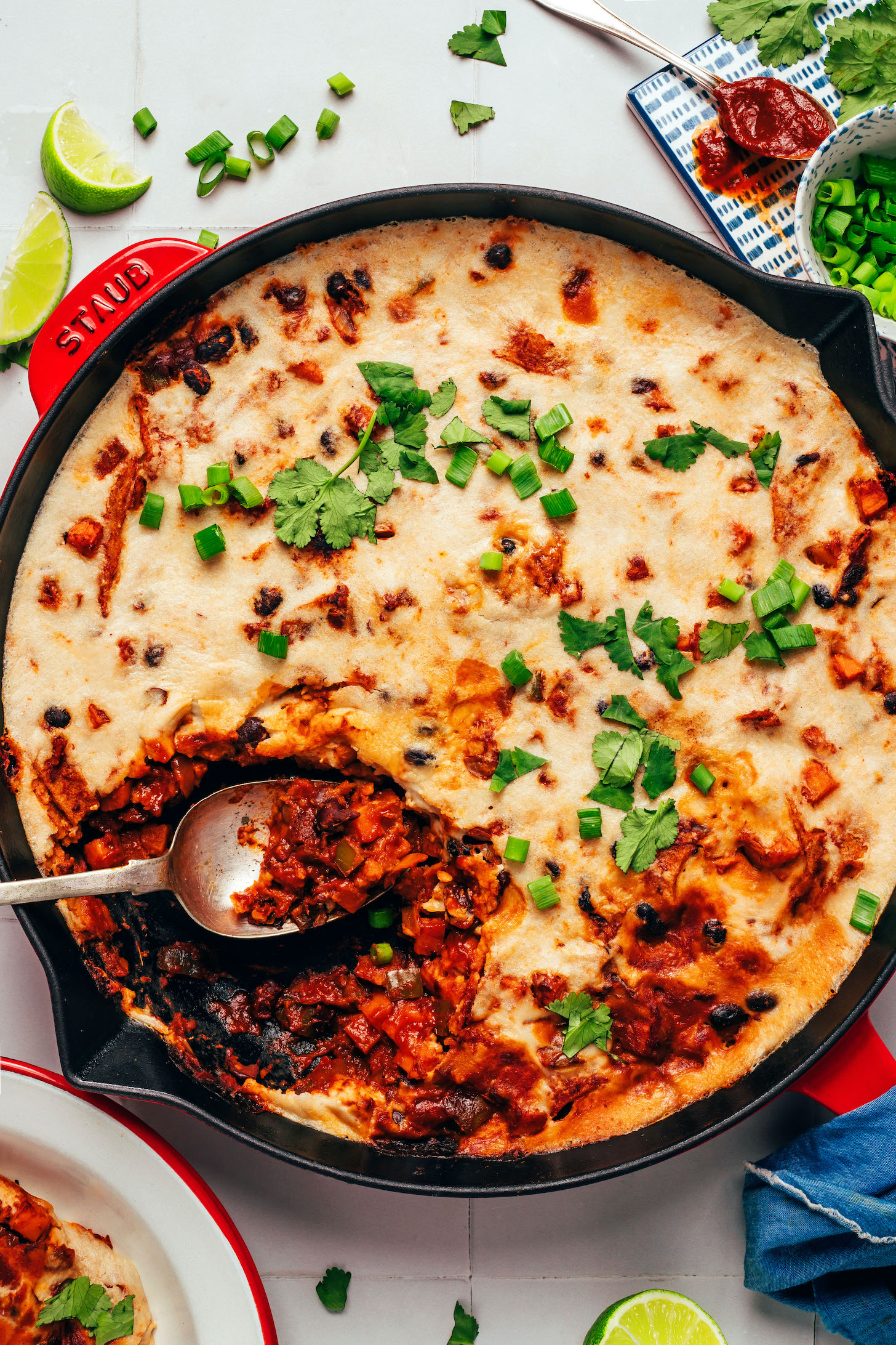 Spoon resting in a pan of our cheesy vegan enchilada skillet recipe