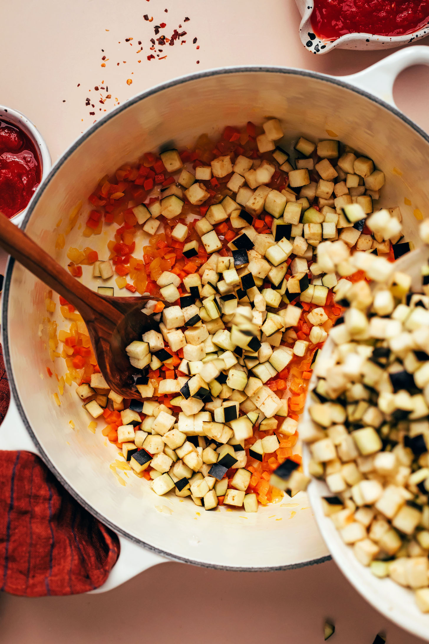 Adding eggplant to a Dutch oven of sautéed onion and carrots